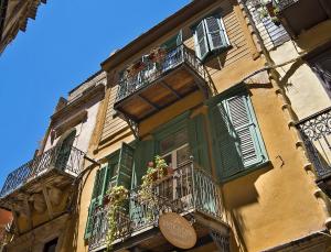 a yellow building with green shutters and balconies at Antica Casa Studios in Chania