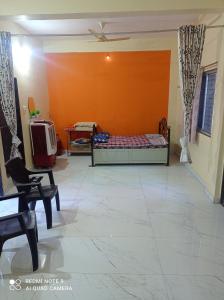 a bedroom with a bed and an orange wall at Masuti Homestay for Swami Bhakts AC room in Akalkot