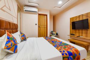 um quarto de hotel com uma cama e uma televisão de ecrã plano em FabHotel The Palace em Vadodara