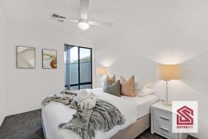 a white bedroom with a bed and a night stand at Bunbury Beach Splendor: Where Dolphins Dance in Bunbury