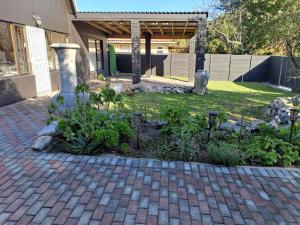a garden with flowers and plants on a brick driveway at Milky Way in Hermanus