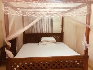 a wooden bed with a canopy with white curtains at Sawa Sawa Apartment in Ngambo
