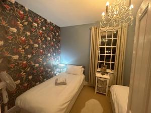 1 dormitorio con 2 camas y pared de flores en Choristers Mews: Luxury cottage a stones throw from the Cathedral!, en Lincolnshire