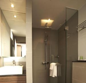 a bathroom with a shower and a sink and a mirror at Sukhumvit Suites Hotel in Bangkok