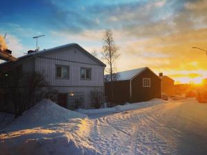 una casa en la nieve con la puesta de sol en el fondo en Lägenhet i lugn trädgård, en Bygdeå