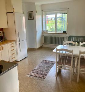 a kitchen with a table and a white refrigerator at Lägenhet i lugn trädgård in Bygdeå