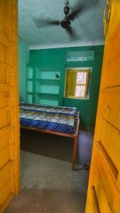 a bed in a green room with a window at ANAND HOSTEL in Pushkar
