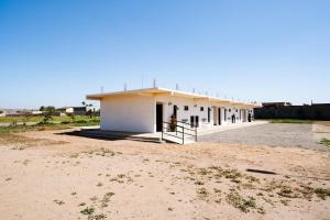 a small white building in the middle of a field at HOTEL & RV PARK ROSA EVELYN in San Quintín