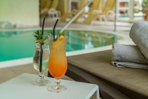 two cocktails sitting on a table next to a pool at Panoramahotel Gürtl in Haus im Ennstal