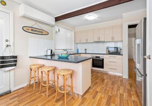 a kitchen with white cabinets and a counter with stools at Paradise on Jones Beach Kiama - Beachfront unit with direct beach access & views in Kiama Downs