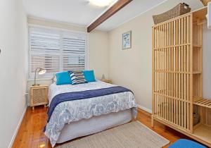 a bedroom with a bed with blue pillows and a window at Paradise on Jones Beach Kiama - Beachfront unit with direct beach access & views in Kiama Downs