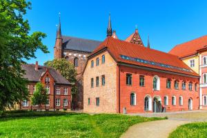 a large brick building with a church in the background at CBlue "Turmresidenz", zentral, familienfreundlich, Schatzsuche in Wismar