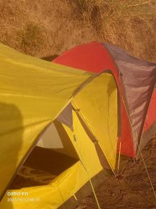 a yellow and red tent sitting in the dirt at Gunung Batur camp in Kintamani