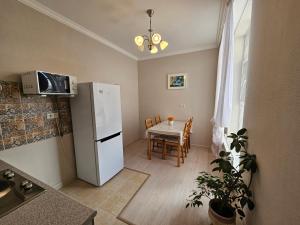 a kitchen with a white refrigerator and a table at Ernaz Plus Apartments: Promenade Expo in Astana