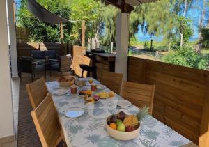a table with a bowl of fruit on a patio at La Villa l'Ancre Marine, pieds dans le lagon ! in La Saline les Bains