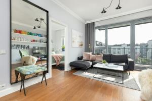 a living room with a black couch and a mirror at Cozy Apartment Gieysztora Wilanów by Renters in Warsaw