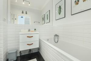 a white bathroom with a tub and a sink at Cozy Apartment Gieysztora Wilanów by Renters in Warsaw