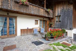 un patio de una casa con 2 sillas y flores en Casa Lacedel 1, on ski slopes en Cortina dʼAmpezzo