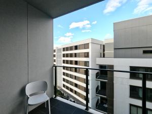 a chair on a balcony with a view of a building at Spacious1 BR@waterfront Olympic Park_free carpark in Sydney