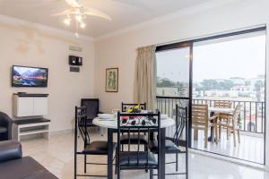 uma sala de estar com uma mesa e cadeiras e uma varanda em Pool & Sea Merill Apartments Mellieha - Happy Rentals em Mellieħa