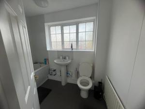a bathroom with a toilet and a sink and a window at The Coral Guest House 1 Mile from Winchester Market in Winchester