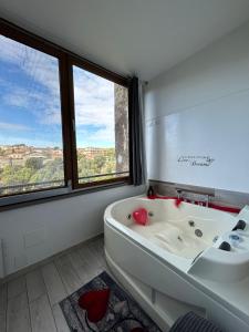 uma casa de banho branca com uma banheira e uma janela em La casa nel Borgo Sospeso "con vasca e vista panoramica" em Vitorchiano