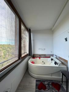 uma banheira branca num quarto com uma janela em La casa nel Borgo Sospeso "con vasca e vista panoramica" em Vitorchiano