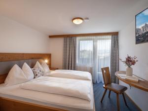 a bedroom with a bed and a desk and a window at Apartment-Pension Schmiedererhof in Sankt Johann in Tirol