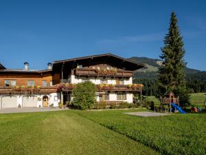 a large house with a playground in front of it at Apartment-Pension Schmiedererhof in Sankt Johann in Tirol