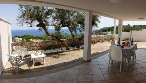 un patio con tavolo, sedie e vista sull'oceano di Dimora Dei Turchesi a Gagliano del Capo