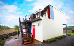 a house with a red door and a staircase at MO Guesthouse in Jeju