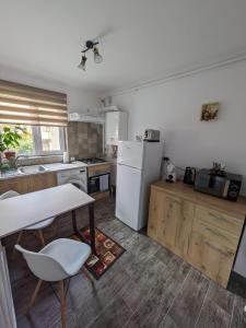 Il comprend une cuisine équipée d'une table et d'un réfrigérateur blanc. dans l'établissement Apartamentul ALFA, à Slănic-Moldova