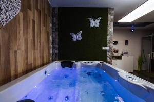 een grote blauwe badkuip met vlinders aan de muur bij Tanja s Holiday Home in Nature with sauna and hot tub in Gorica pri Slivnici