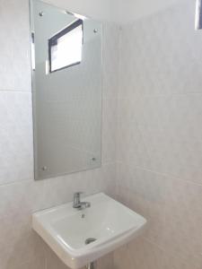 a white bathroom with a sink and a mirror at BTN Mahkota Pemenang 13 Tamarin 3A in Pawenang