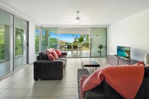 a living room with two couches and a television at Azure Sea Whitsunday Resort in Airlie Beach