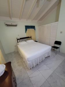 1 dormitorio con 1 cama blanca grande y 1 silla en Tropical Blessings - Ocho Rios en St Mary