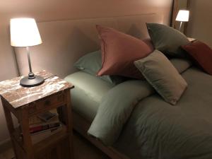 a bed with pillows and a table with a lamp at NeNe in Dilbeek