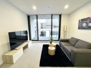 salon z kanapą i telewizorem z płaskim ekranem w obiekcie Spacious1 BR@waterfront Olympic Park_free carpark w mieście Sydney