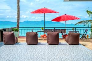 eine Gruppe von Stühlen und Sonnenschirmen am Strand in der Unterkunft The Florist Resort in Mae Nam