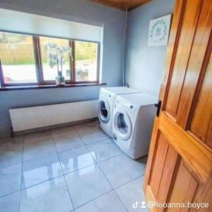 a laundry room with a washing machine and a window at Under Gáinne in Cloghbane