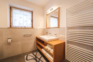bagno con lavandino e specchio di Elslerhof a Dobbiaco