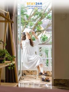 a woman sitting on a chair in front of a window at RAON Villa - STAY 24H in Da Lat