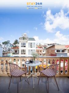 a table and chairs on a balcony with a view of a city at AN Boutique Hotel - STAY 24H in Da Lat