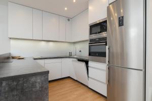 a kitchen with white cabinets and a stainless steel refrigerator at Spacious Apartment for 6 Guests in Krakow with Home Office by Renters in Krakow