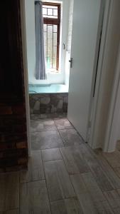 a bathroom with a window and a tile floor at Hidden Cottage in Bredasdorp