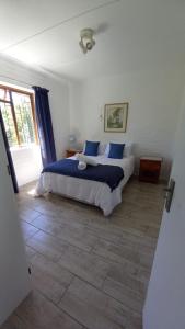 a bedroom with a large bed with blue pillows at Hidden Cottage in Bredasdorp