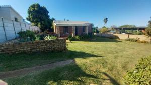 a yard with a brick fence and a house at Hidden Cottage in Bredasdorp