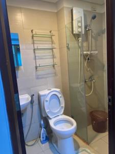 uma casa de banho com um WC e uma cabina de duche em vidro. em anuva residences em Manila