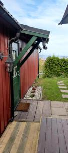 una terrazza in legno con una porta verde su un edificio di Lille huset a Holmestrand