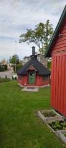 a red house with a black roof next to a yard at Lille huset in Holmestrand